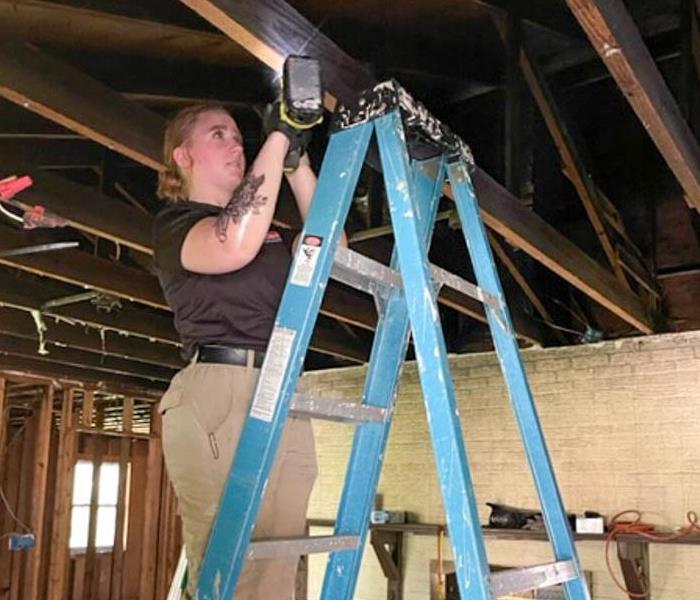 SERVPRO employee standing on a ladder.
